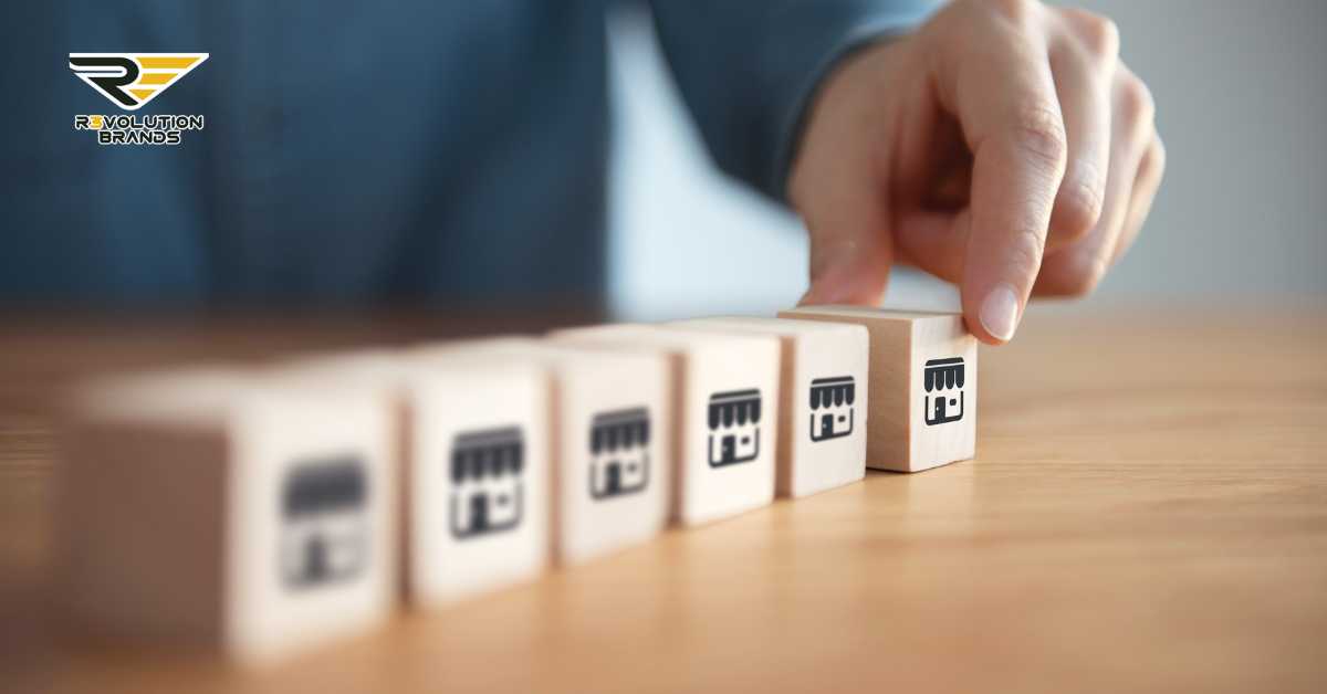 A close-up image of a hand arranging wooden blocks with franchise shop icons, set on a table. The scene symbolizes strategic business expansion and the careful building of a franchise network. The R3volution Brands logo is subtly placed in the upper left corner, suggesting a focus on innovative franchising solutions.