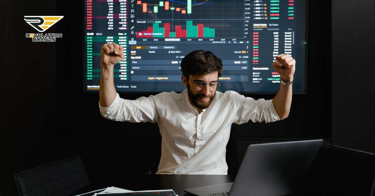 A jubilant young businessman in a white shirt and glasses celebrates success in front of multiple screens showing dynamic stock market charts and trading data. His fists are raised in victory, reflecting his elation at positive financial results. This image captures a moment of triumph, likely in a context of franchise success analysis, with the R3volution Brands logo in the upper left corner emphasizing a focus on data-driven decision making in franchising.